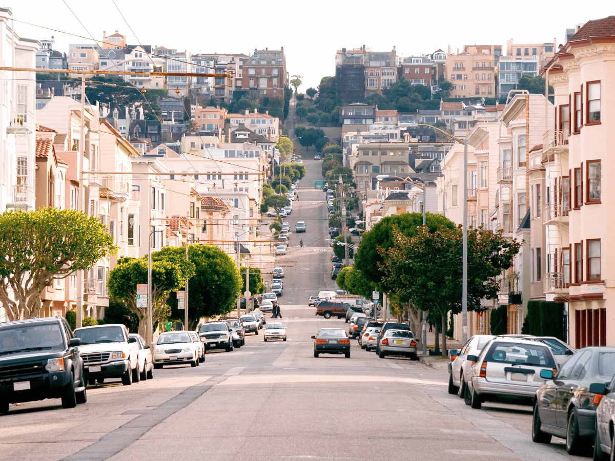 Street-level view of Fillmore, California with residential homes, parked cars, and tree-lined city streets.