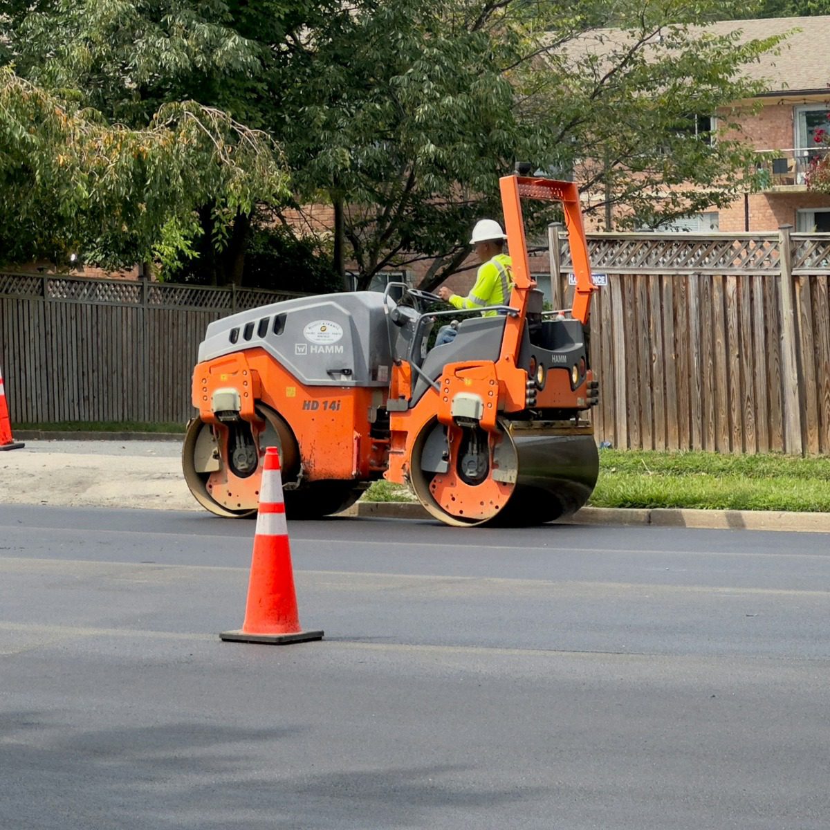 Road construction worker operating a heavy roller on a freshly paved roadway, representing professional municipal street sweeper services in Thousand Oaks, CA.