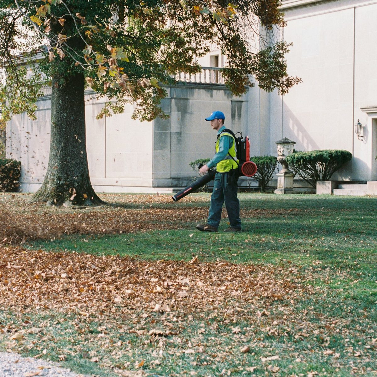 Grounds maintenance worker clearing fallen leaves with a leaf blower for HOA Sweeping near me