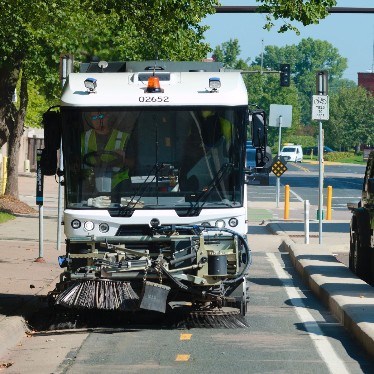 Municipal street sweeper truck cleaning a curbside roadway near me
